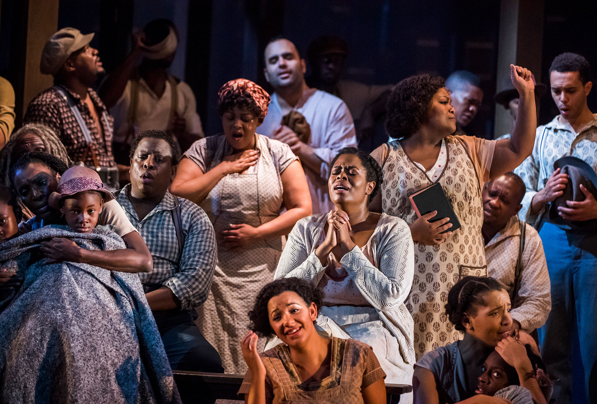Group of black performers praying on stage