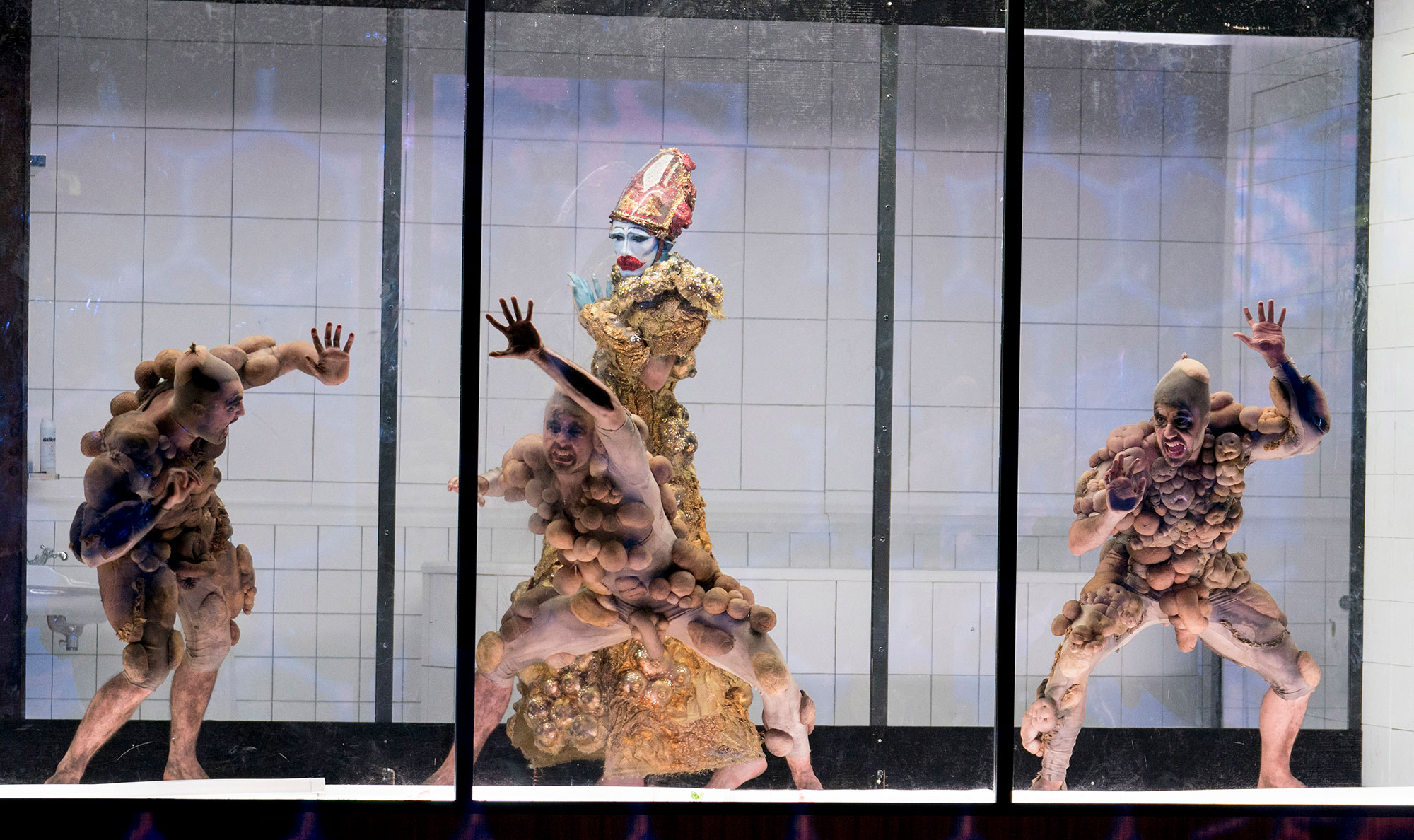4 characters behind glass on stage