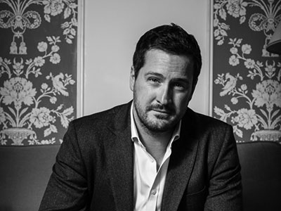 George von Bergen sitting against a patterned backdrop