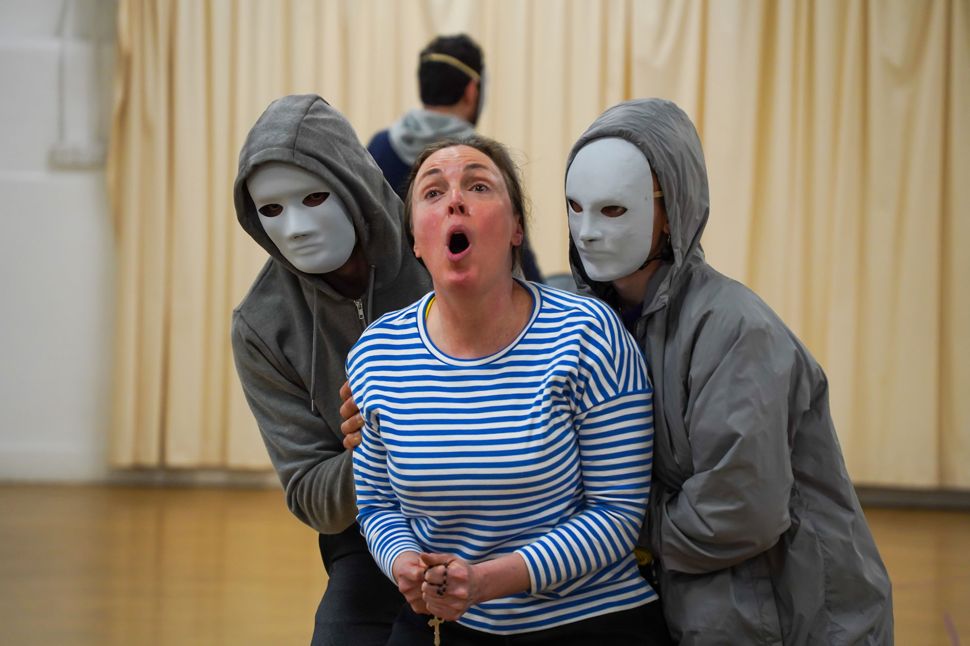 People in masks holding a woman
