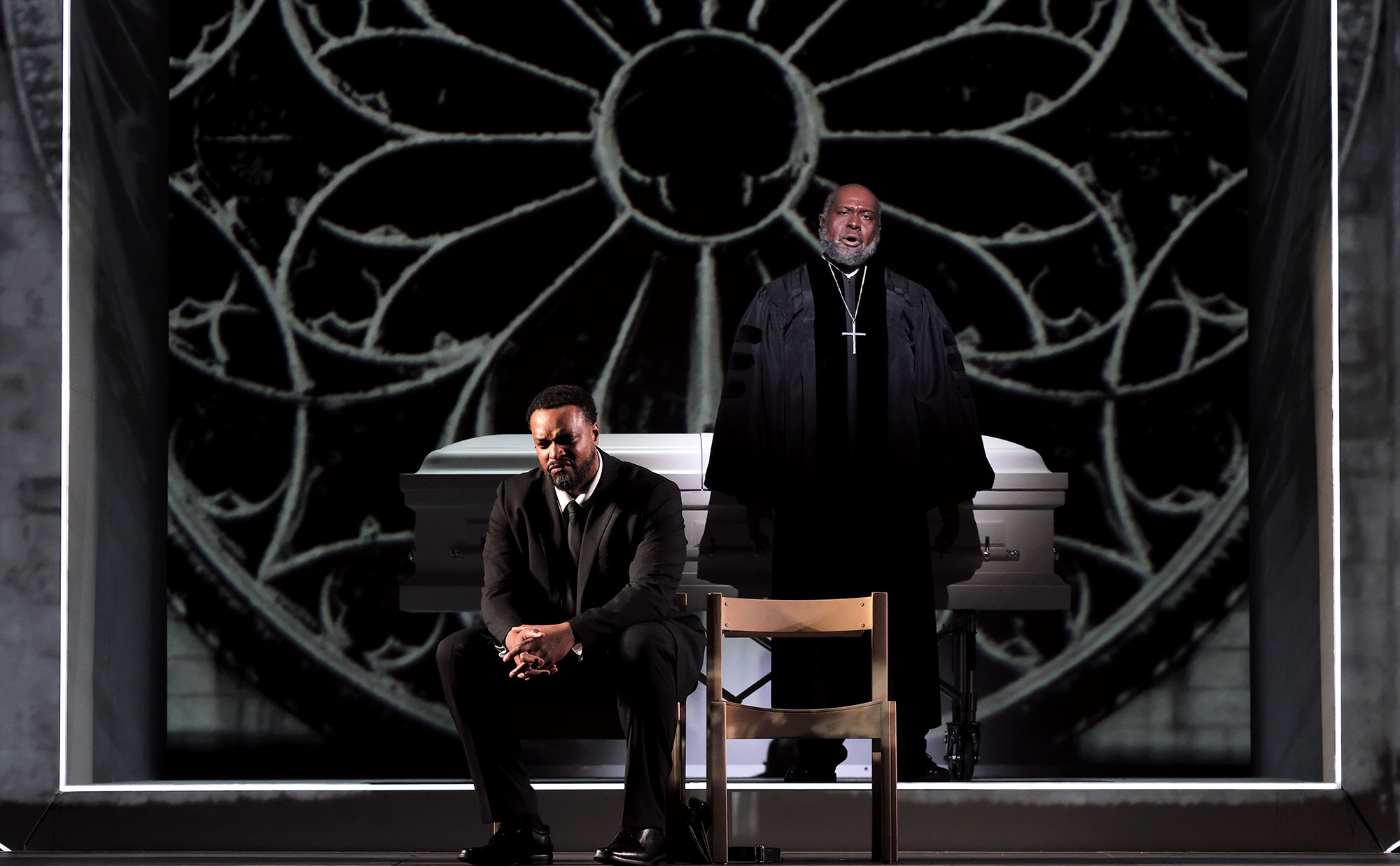 Priest singing and another man sitting down