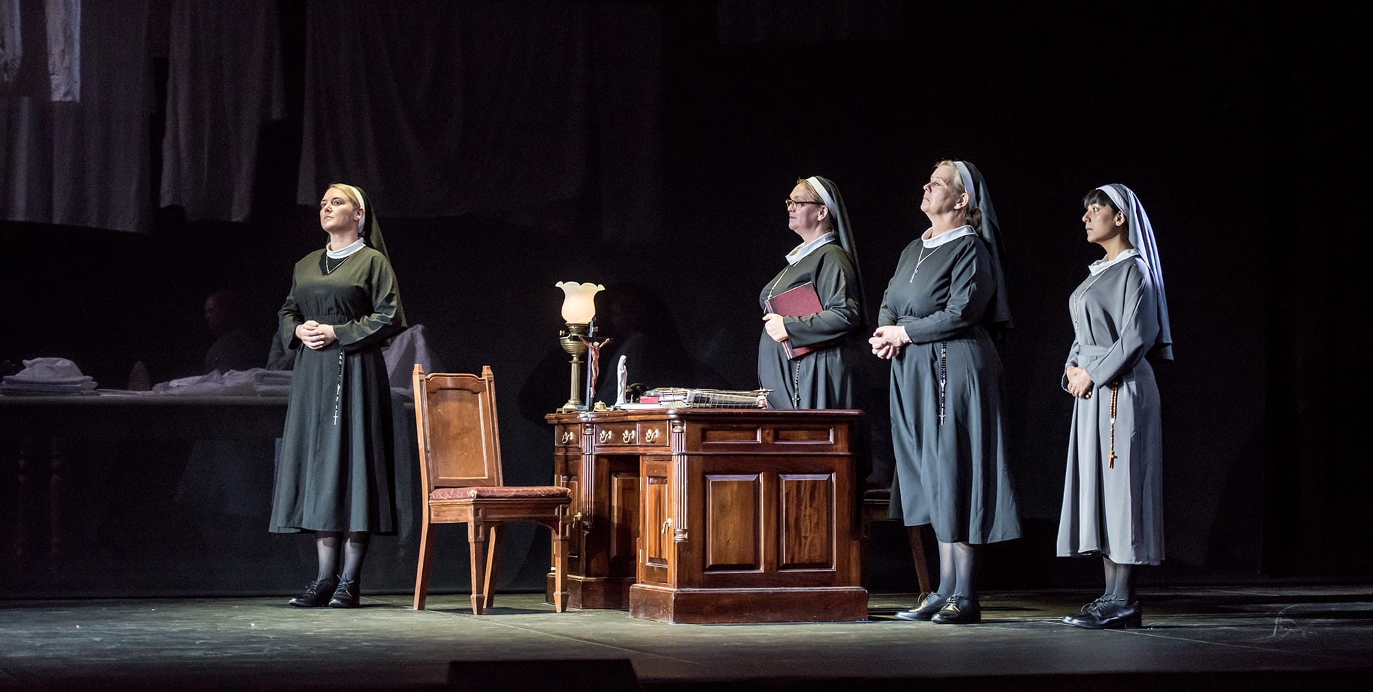 4 nuns standing in a room around a desk