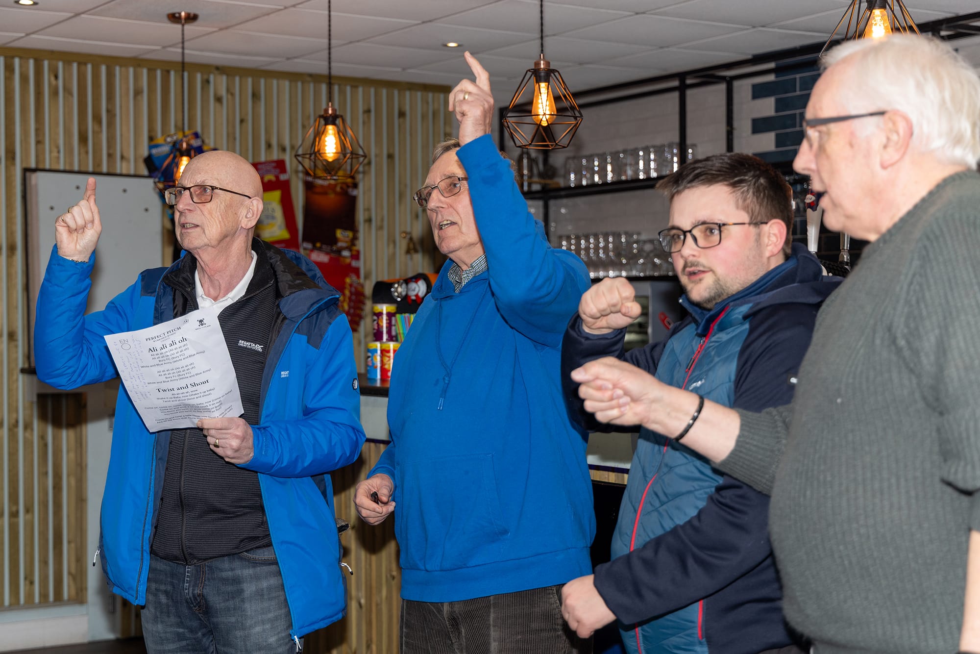 Perfect Pitch - Image of men gesturing with their arms while singing